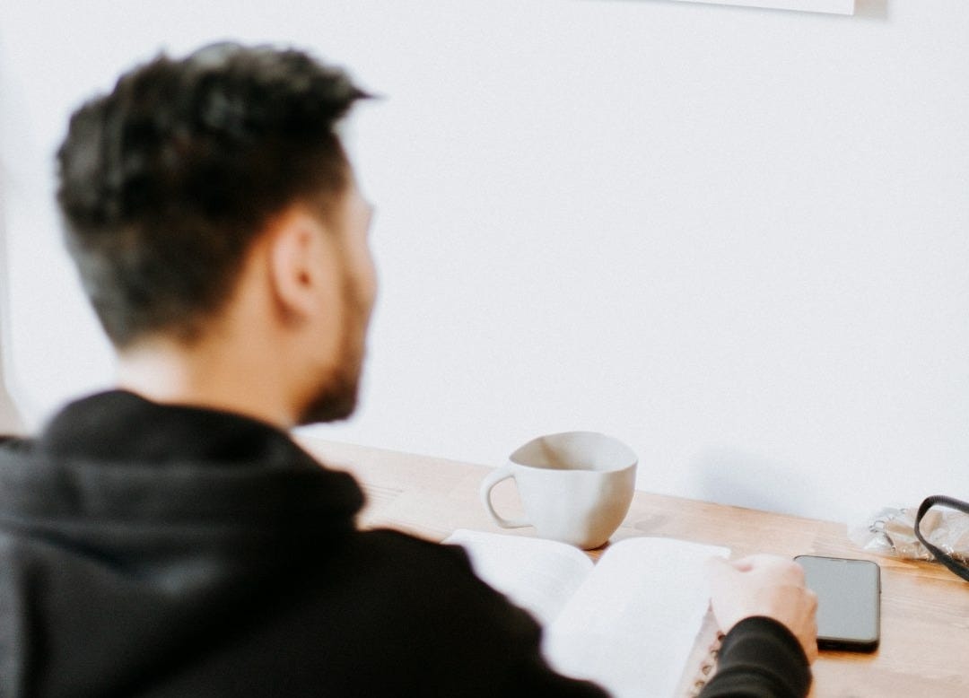 a man sitting at a desk with a cup of coffee a man sitting at a desk with a cup of coffee