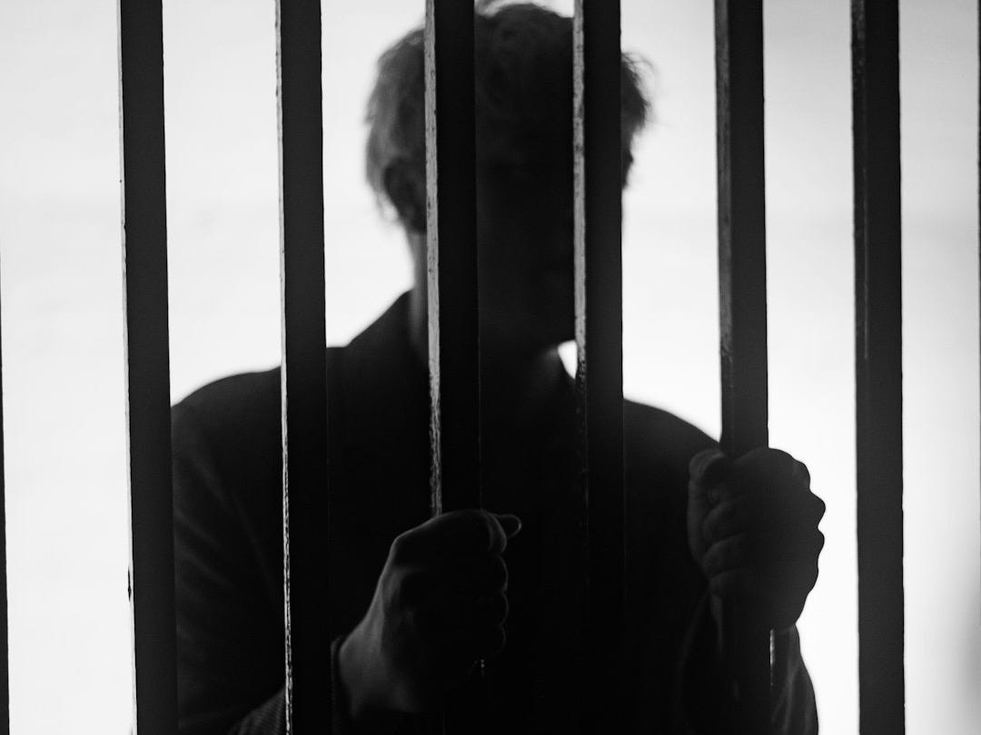 a man standing behind bars in a jail cell