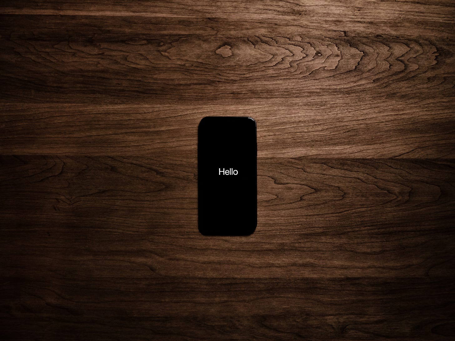 Phone on wood background with hello displayed on the screen Phone on wood background with hello displayed on the screen