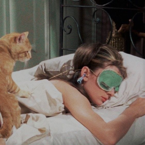 This may contain: a woman laying in bed with a cat next to her