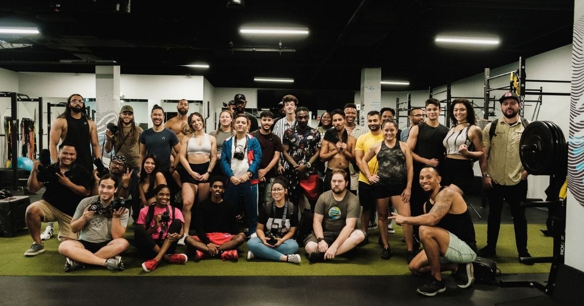 A large group of adults smiling and posing together in a gym setting