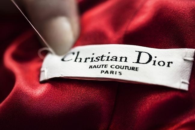 Cosiendo la etiqueta en un vestido rojo de Christian Dior, marca de lujo.