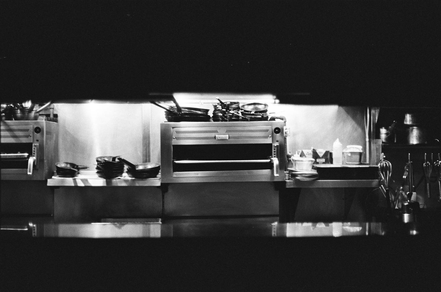 35mm black & white film photograph of a restaurant kitchen after service taken from the pass.