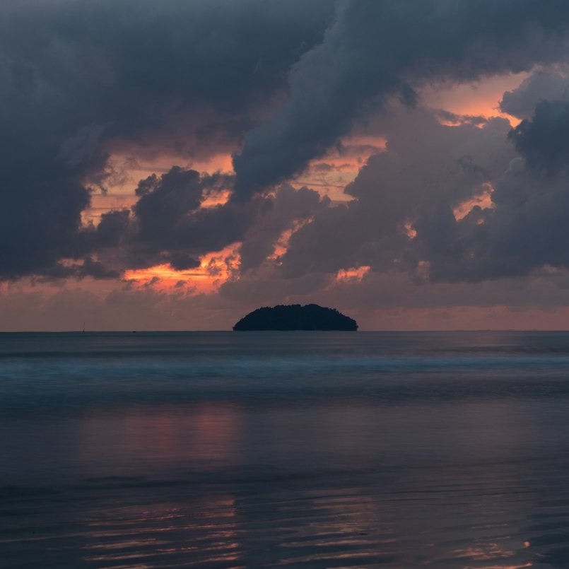 photo island under cloudy sky during golden hour