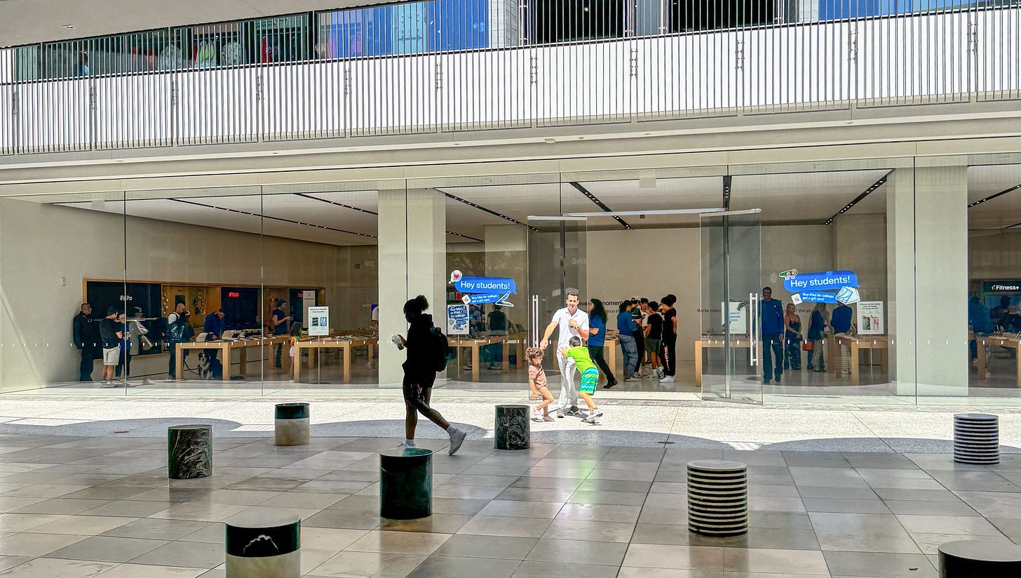A large white barricade surrounds the Forum at Apple Century City. People are walking in front of the store. A large white barricade surrounds the Forum at Apple Century City. People are walking in front of the store.