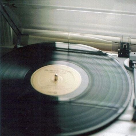 This may contain: an old record player sitting on top of a white table next to a pair of scissors