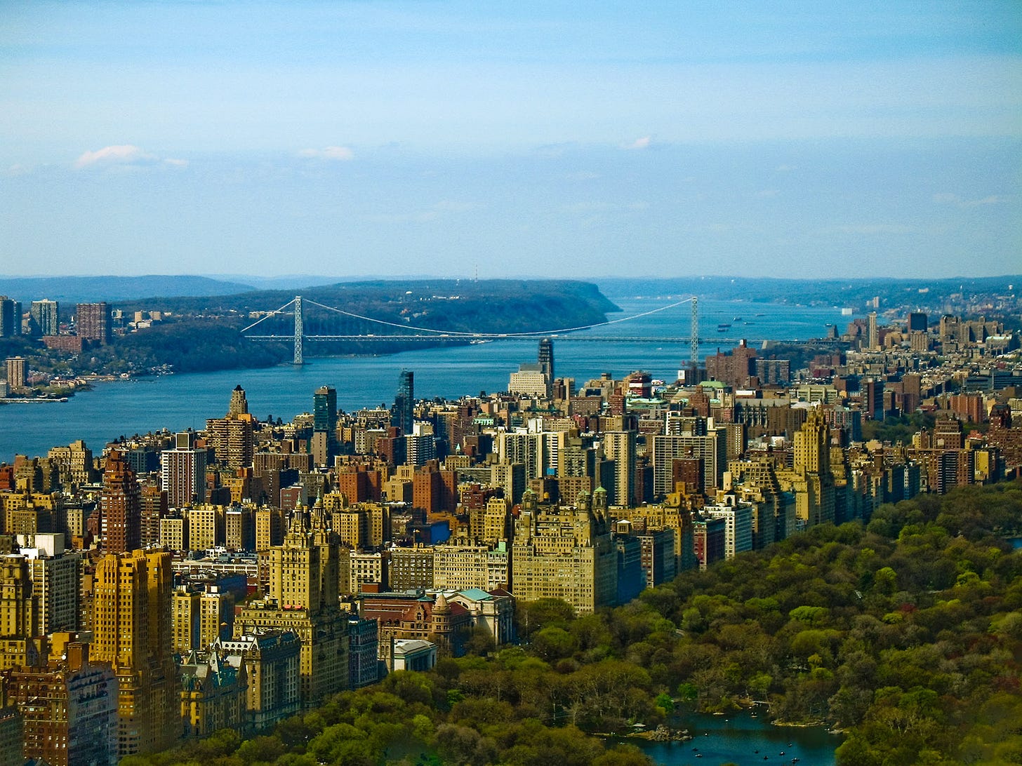 NYC view from top of skyscraper with George Washington Bridge and mountains beyond