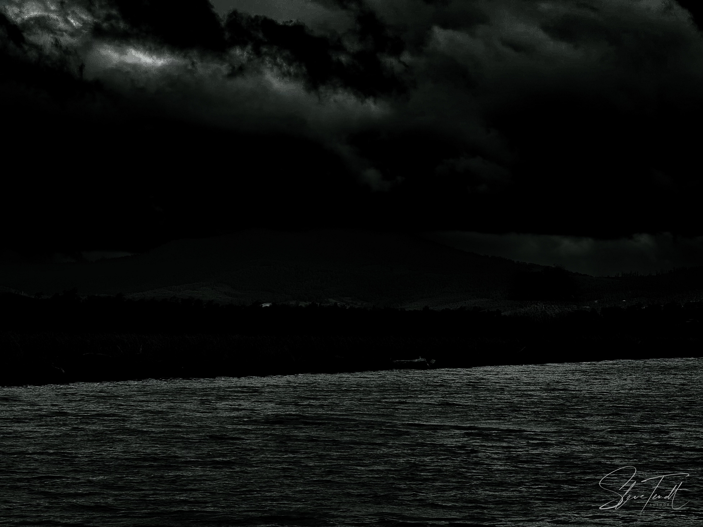 Nocturnal scene: broad river in the foreground, under a cloudy sky; the far bank barely discernible in shadow.