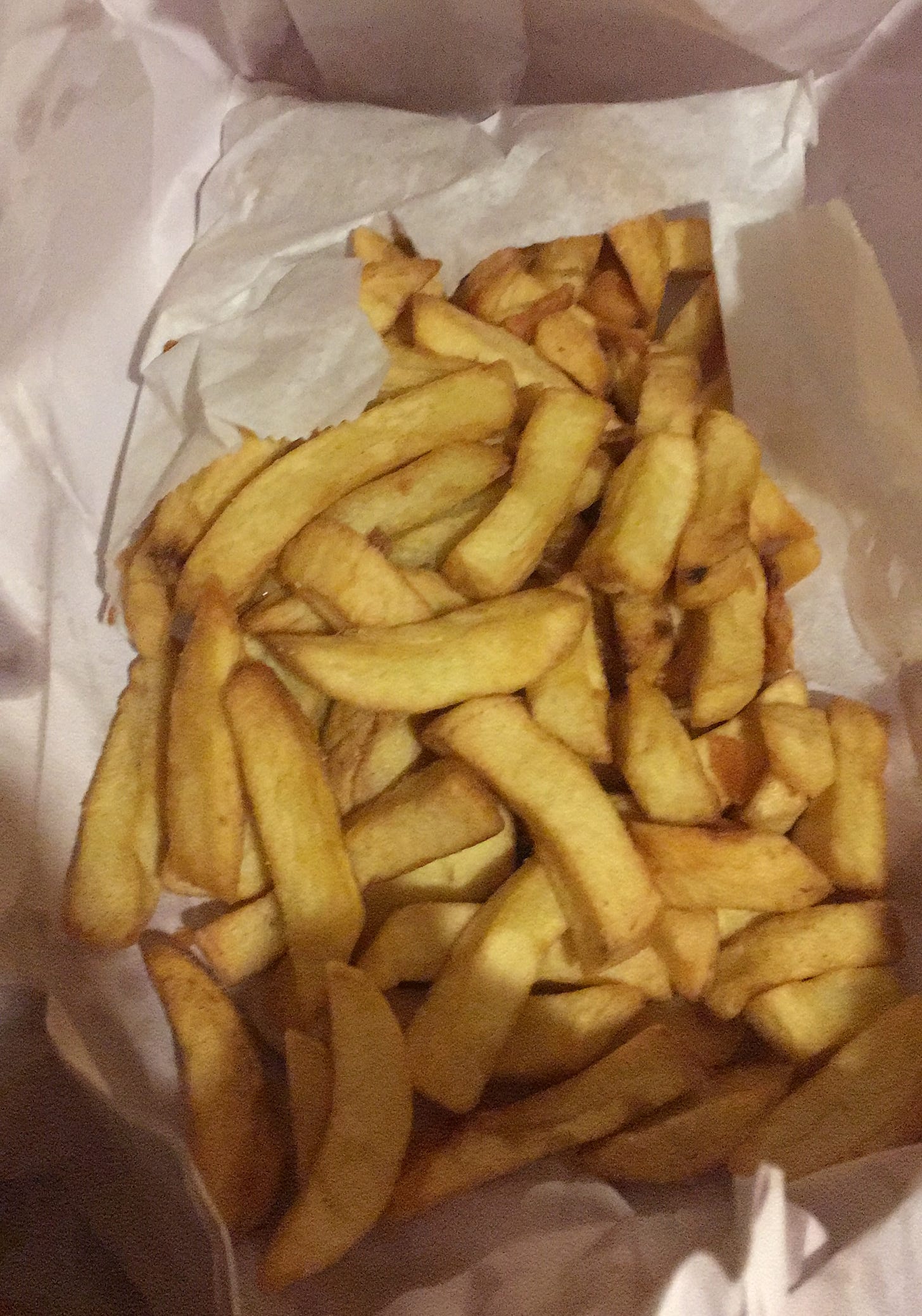 Fat yellow chips in a white paper bag Fat yellow chips in a white paper bag