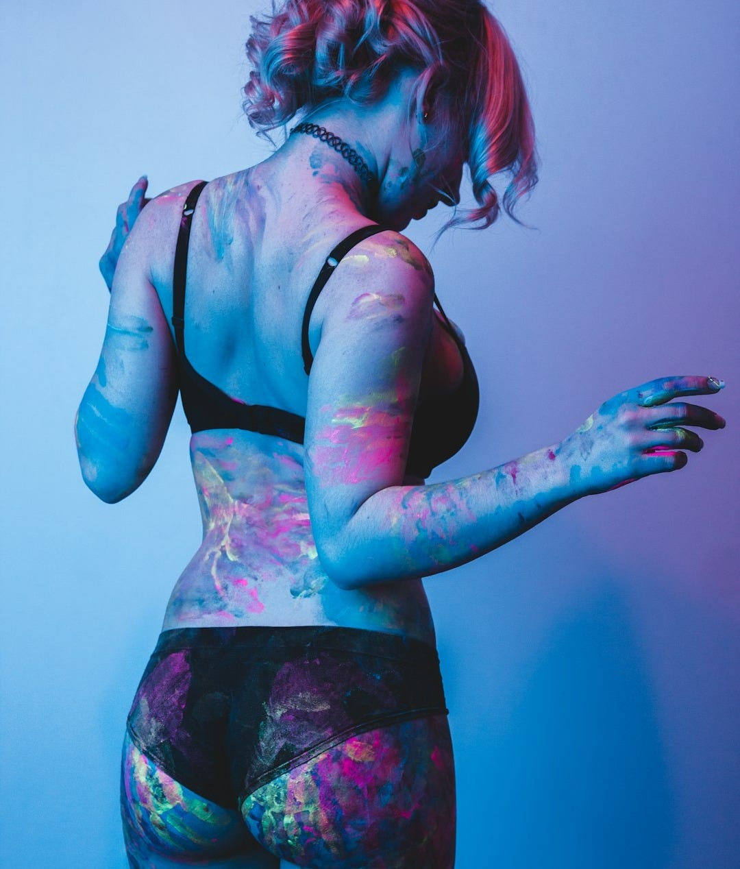woman with paint on her body facing the wall woman with paint on her body facing the wall