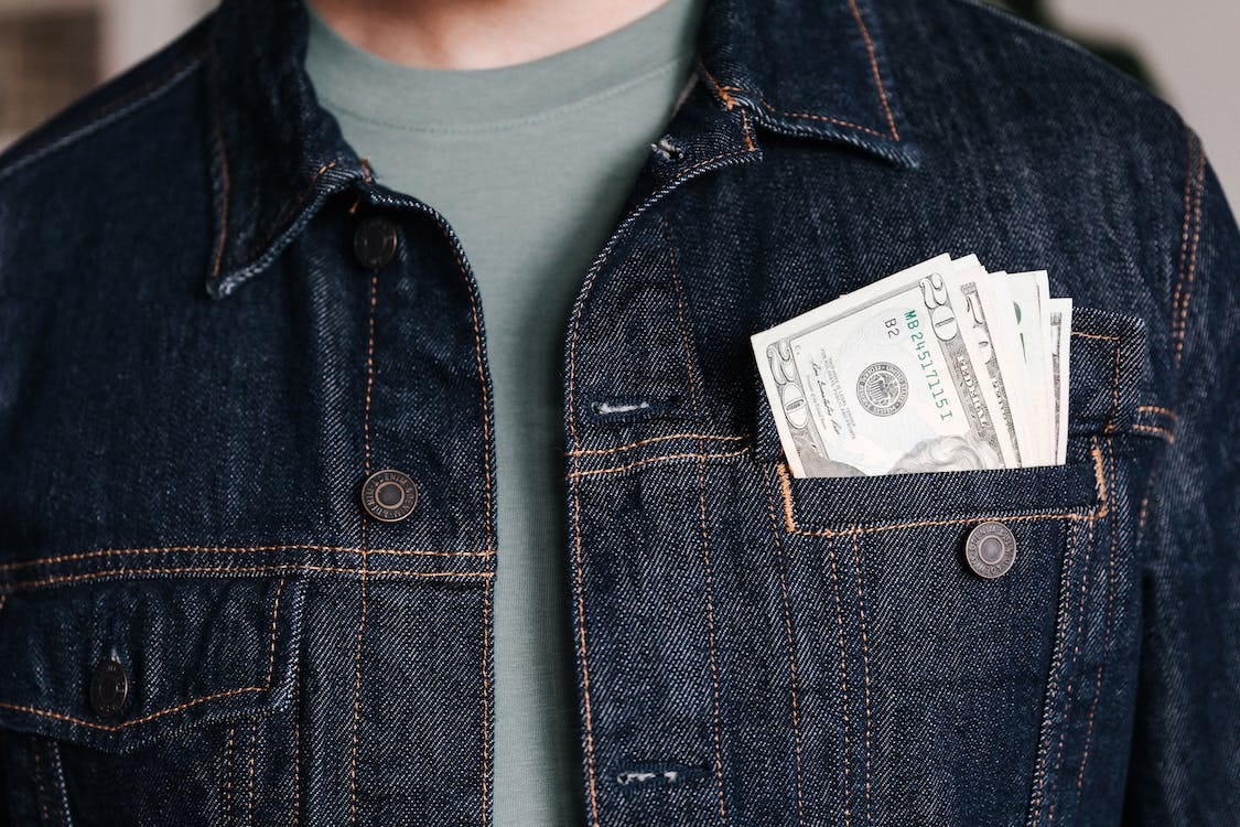 Free Crop unrecognizable male in casual outfit standing with different nominal pars of dollar banknotes in pocket of jeans jacket Stock Photo Free Crop unrecognizable male in casual outfit standing with different nominal pars of dollar banknotes in pocket of jeans jacket Stock Photo