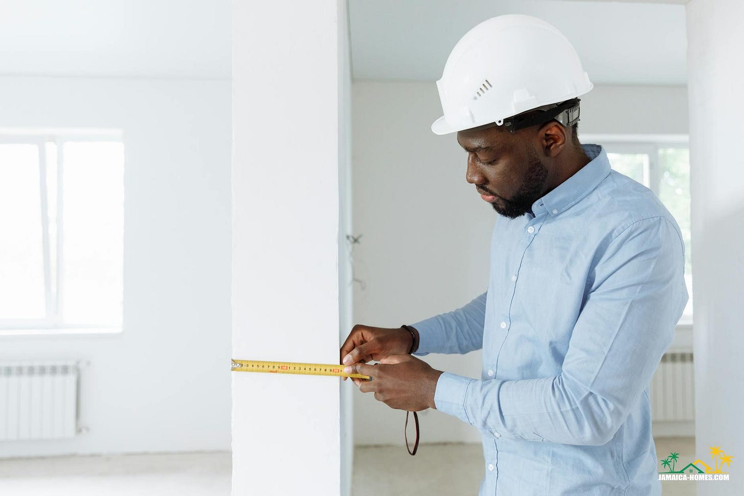 a man in blue long sleeves wearing a hard hat while holding a measuring tape