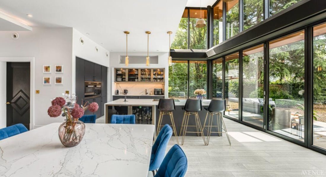 A kitchen with a marble dining table, black cabinets, and floor-to-ceiling windows A kitchen with a marble dining table, black cabinets, and floor-to-ceiling windows