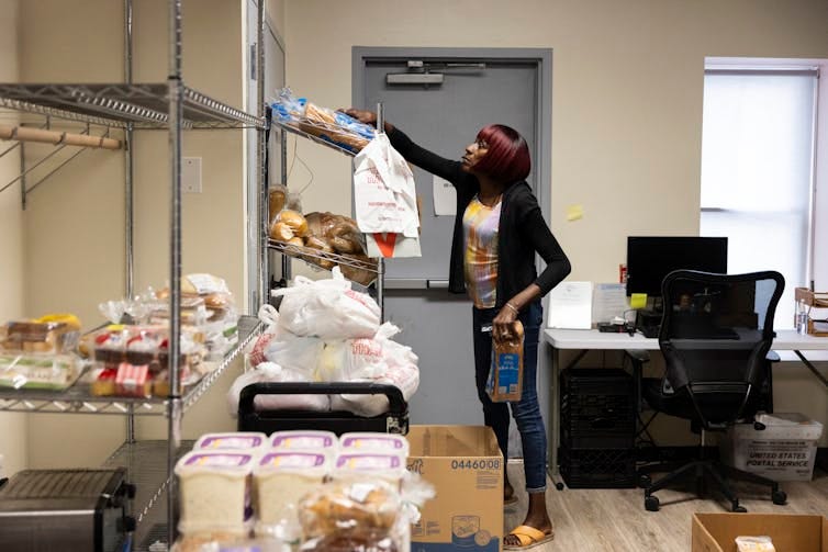 Woman reaches for loaf of bread on shelf that contains food products
