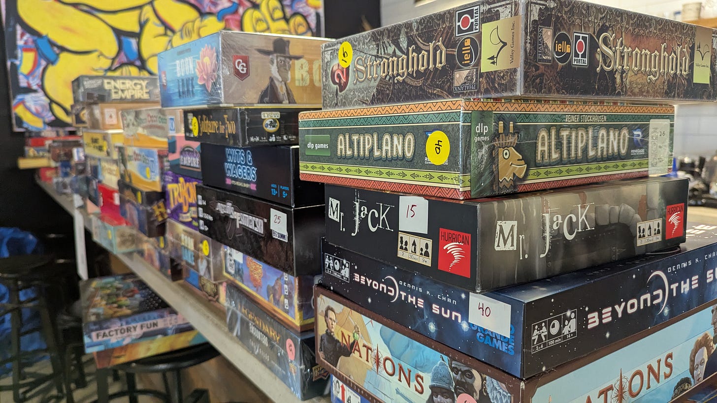 shelves filled with hobby board games such as Nations, Wits and Wagers, Altiplano shelves filled with hobby board games such as Nations, Wits and Wagers, Altiplano
