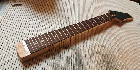 Pictures of the cutout body blank and the neck before and after the fingerboard is glued.