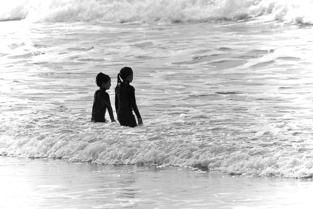 A couple of children standing in the water

AI-generated content may be incorrect.