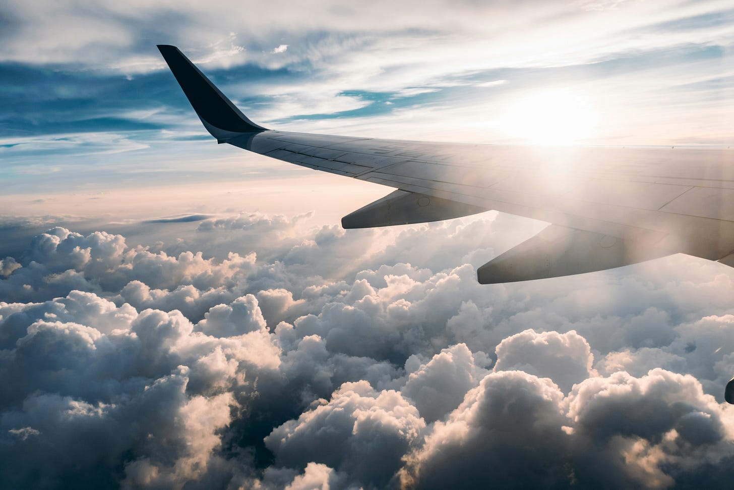 Image of an aircraft wing above the clouds at sunset.