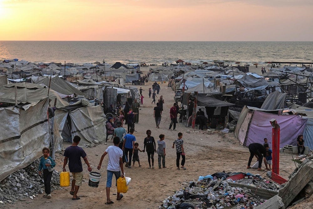 Displaced Palestinians walk through a makeshift camp along the beach in Gaza City, Sunday, Aug. 10, 2025 (AP)