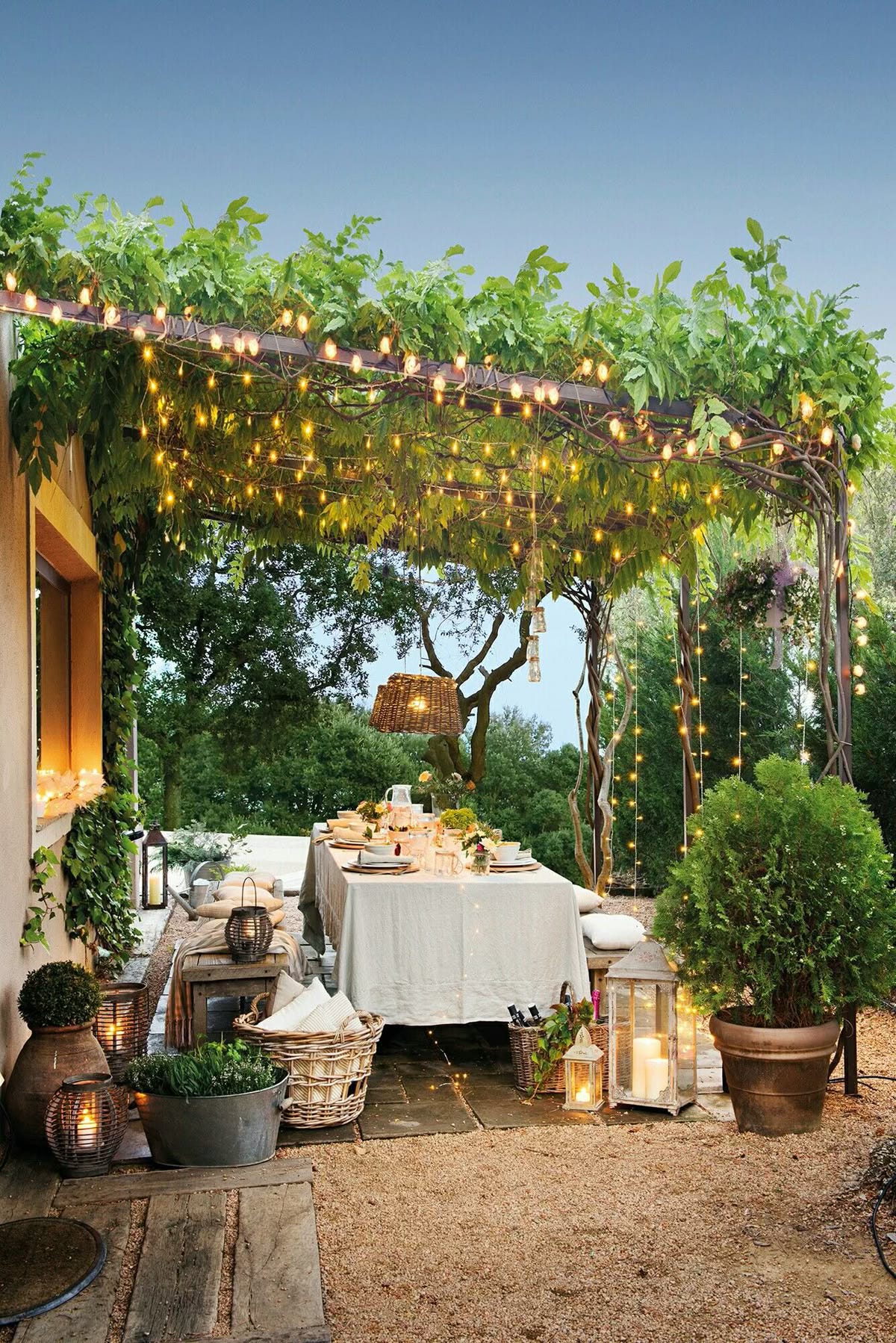 a welcoming dining area in a garden with a pergola and fairy lights