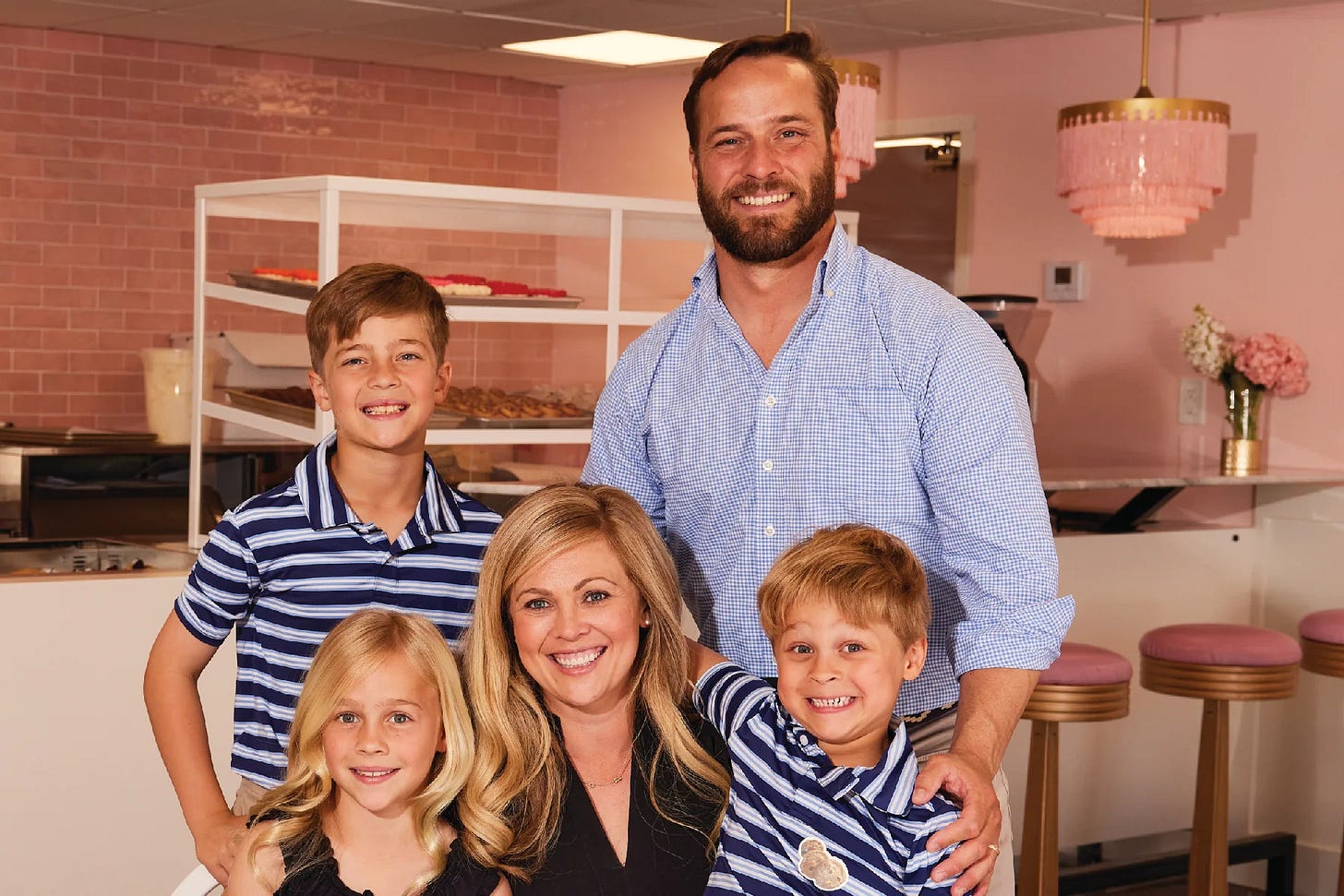 Ashley, her husband and three kids Hank, Charlie and Carlisle in the light pink kitchen with trays off cookies cooling in the background Ashley, her husband and three kids Hank, Charlie and Carlisle in the light pink kitchen with trays off cookies cooling in the background