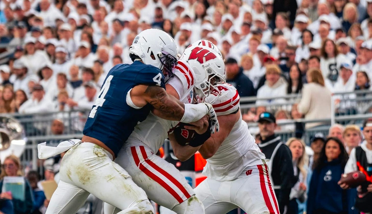 Wisconsin Badgers quarterback Colton Joseph carries the ball while being tackled by a Penn State defender.