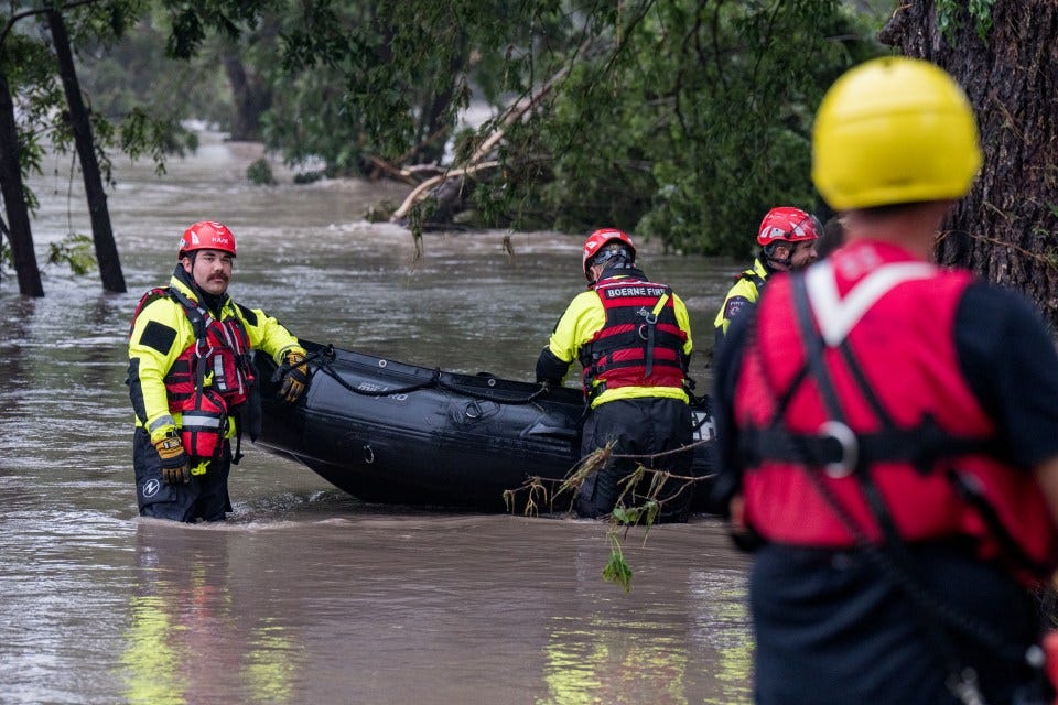 Boerne search and rescue team members carrying an inflatable boat through floodwaters.