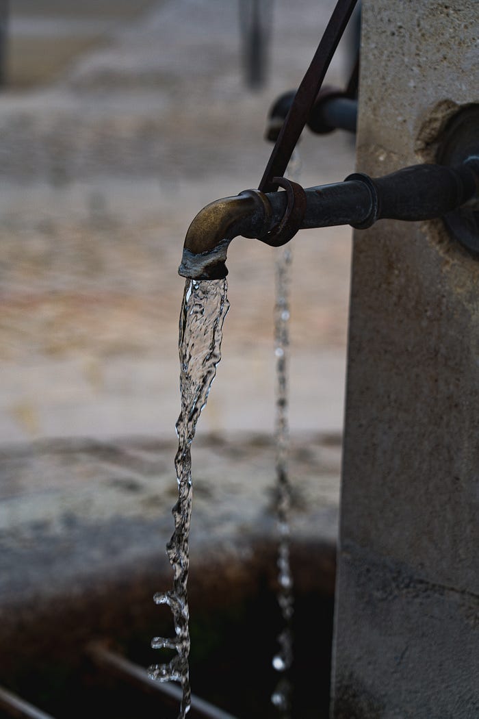 An old spout offering water for people to pump and collect. An old spout offering water for people to pump and collect.
