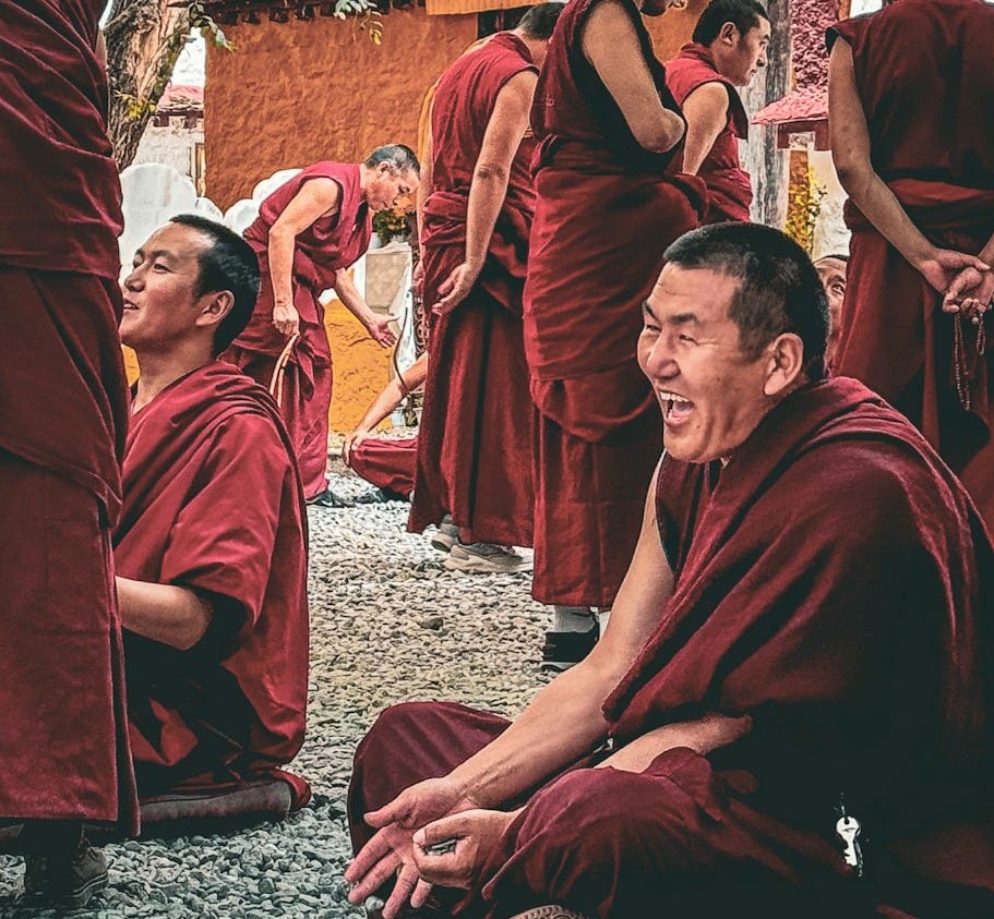 Monks are laughing and conversing outside. Monks are laughing and conversing outside.