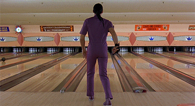 Gif dal film "Il grande Lebowski" con John Turturro nei panni di Jesus, vestito tutto di violetto su una pista di bowling, mentre ci guarda con aria di sfida e accenna un passo di danza.