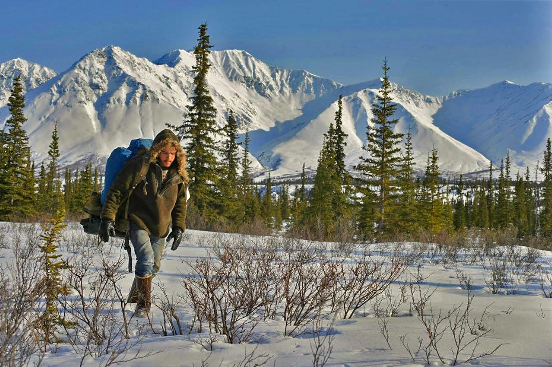 man walking, snowy landscape, mountains above