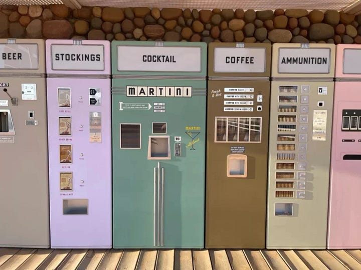 Cardboard box painted to look like a Martini vending machine & an image of the vending machines from Asteroid City for stockings, cocktails, coffee & ammunition.