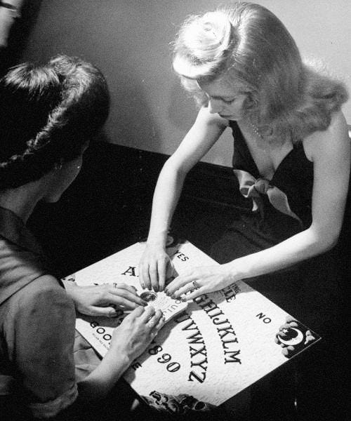 This may contain: two women sitting at a table with a cake in front of them and the words cemetery gates written on it