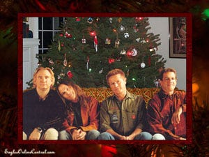 The four members of the band the Eagles sitting on a couch in front of a Christmas tree.