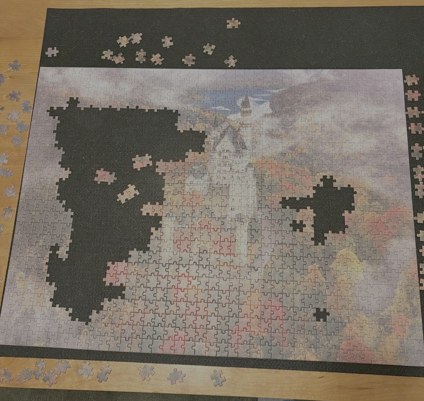 An unfinished 1000-piece jigsaw puzzle. The art is a drone shot of Neuschwanstein Castle surrounded by autumn foliage.