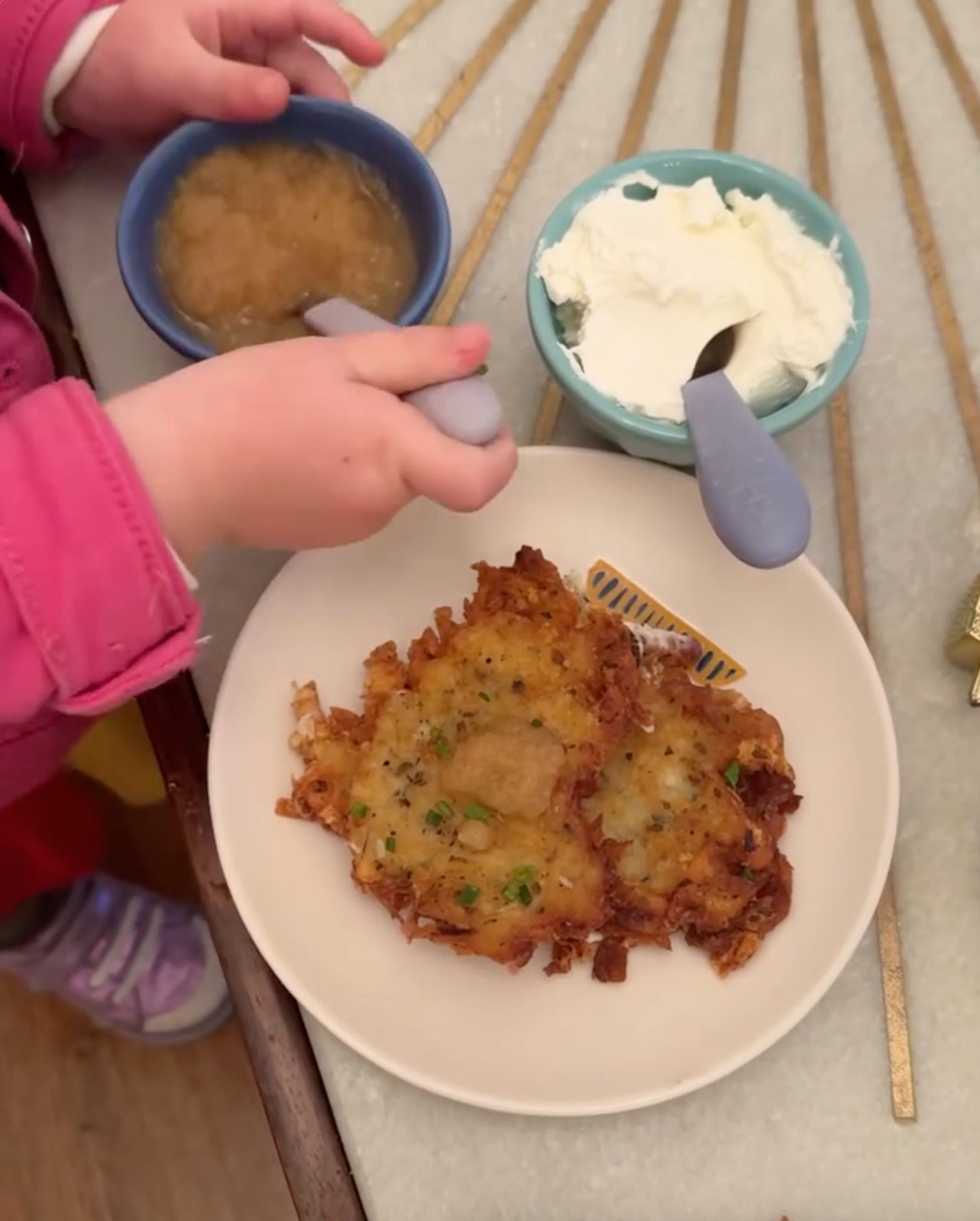 Latkes on a white plate with applesauce and sour cream on the side