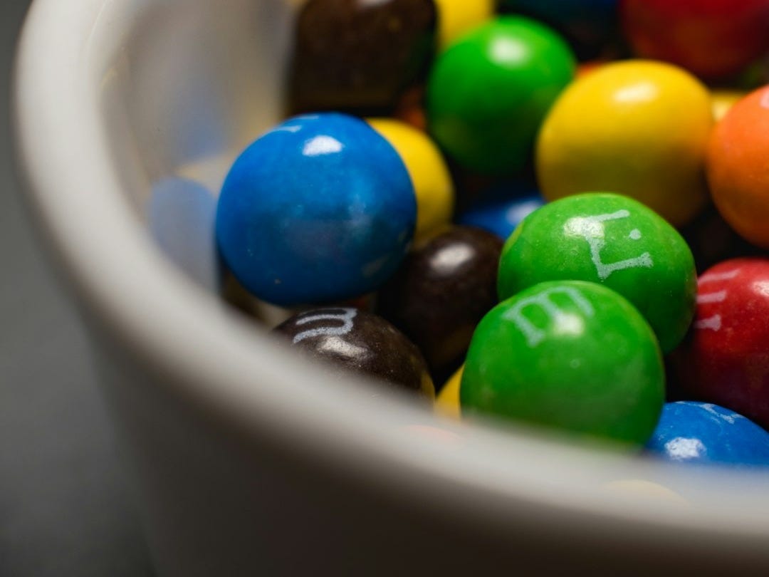 a white bowl filled with lots of colorful candy