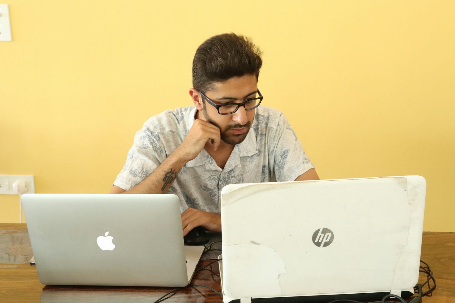 A man works at a desk using two laptops at once, symbolizing digital hoarding and information overload. Photo by Shivam Gandhi on Unsplash