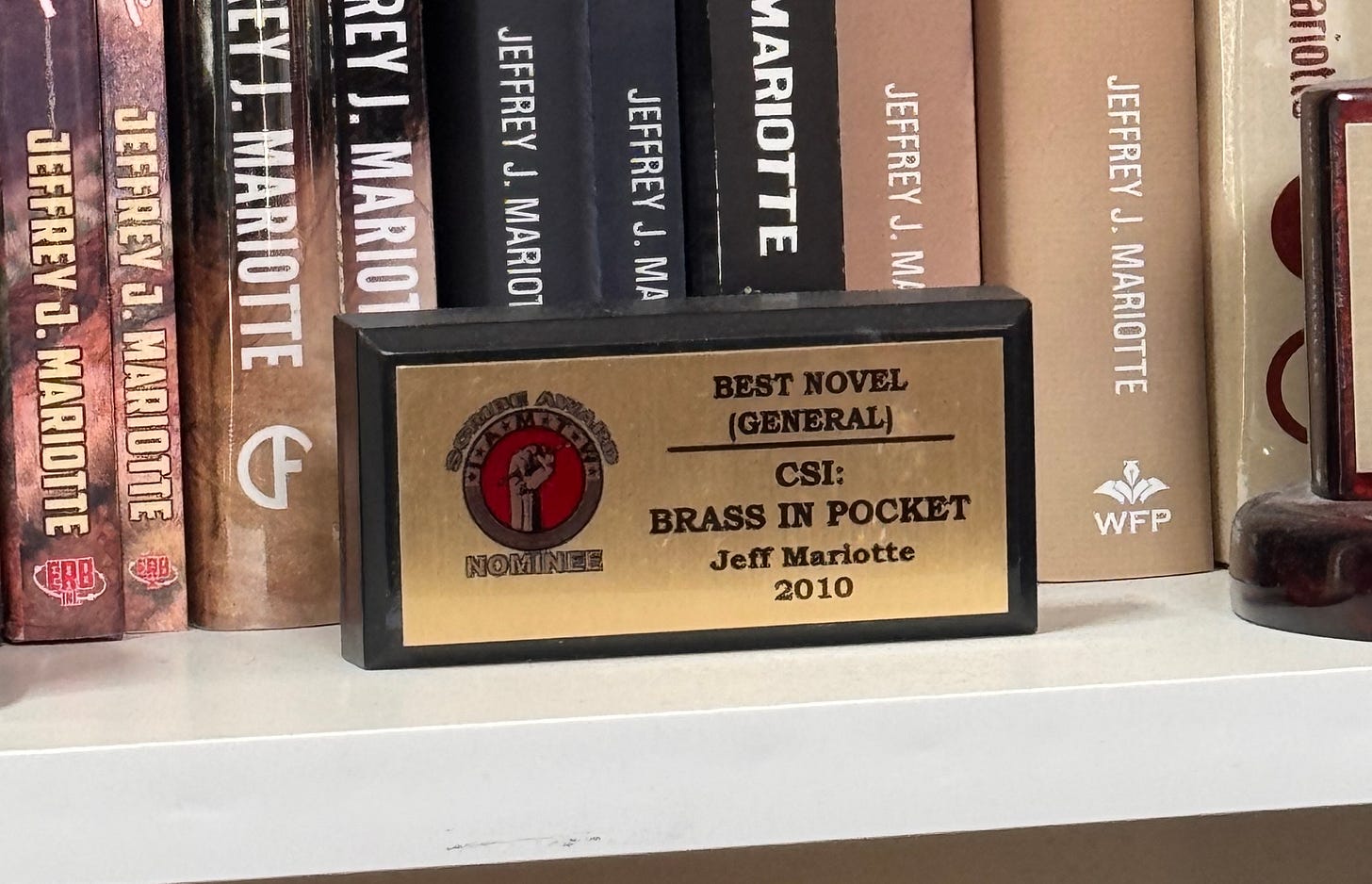 A small rectangular trophy standing on a bookshelf