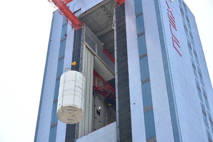 The Long March 3B/E's booster and fairing being prepared for the mission, and the ChinaSat-9C satellite being hoisted toward the top of the vehicle.