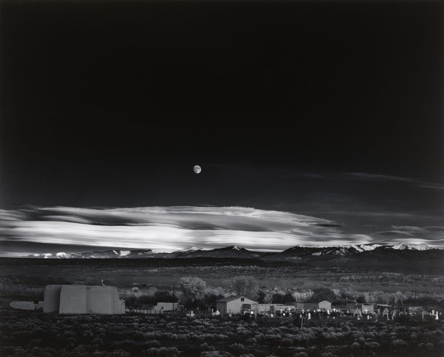 A moon over a mountain range

Description automatically generated