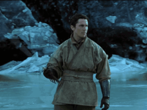 a man in a kimono and gloves stands in front of a frozen body of water a man in a kimono and gloves stands in front of a frozen body of water