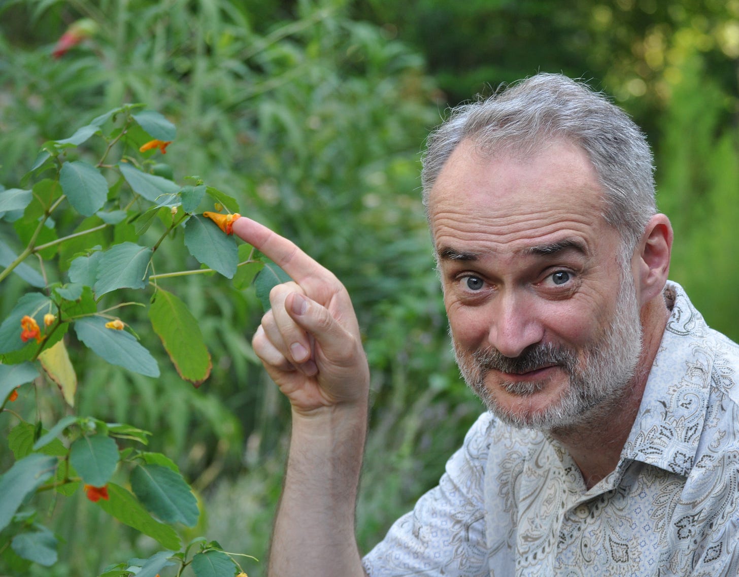 Image of David George Haskell pointing out a flower