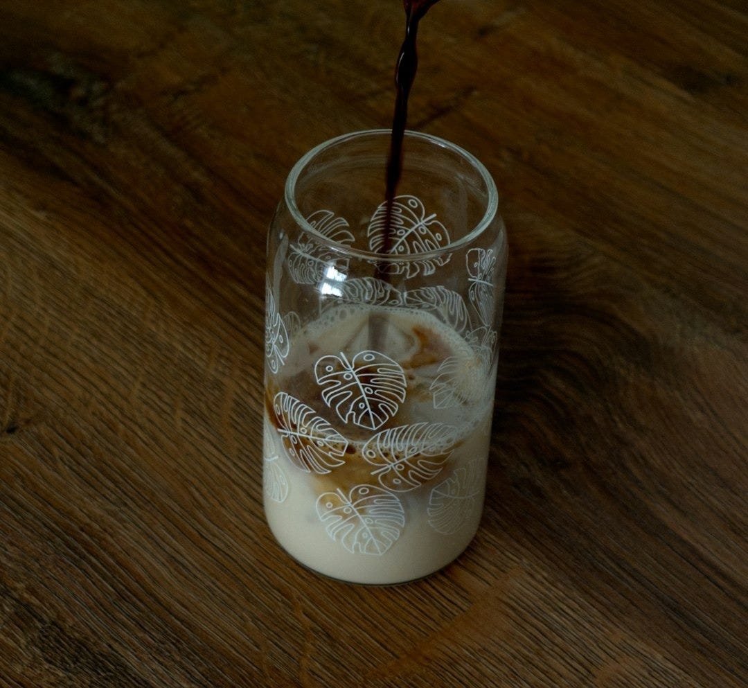 A glass filled with liquid sitting on top of a wooden table A glass filled with liquid sitting on top of a wooden table
