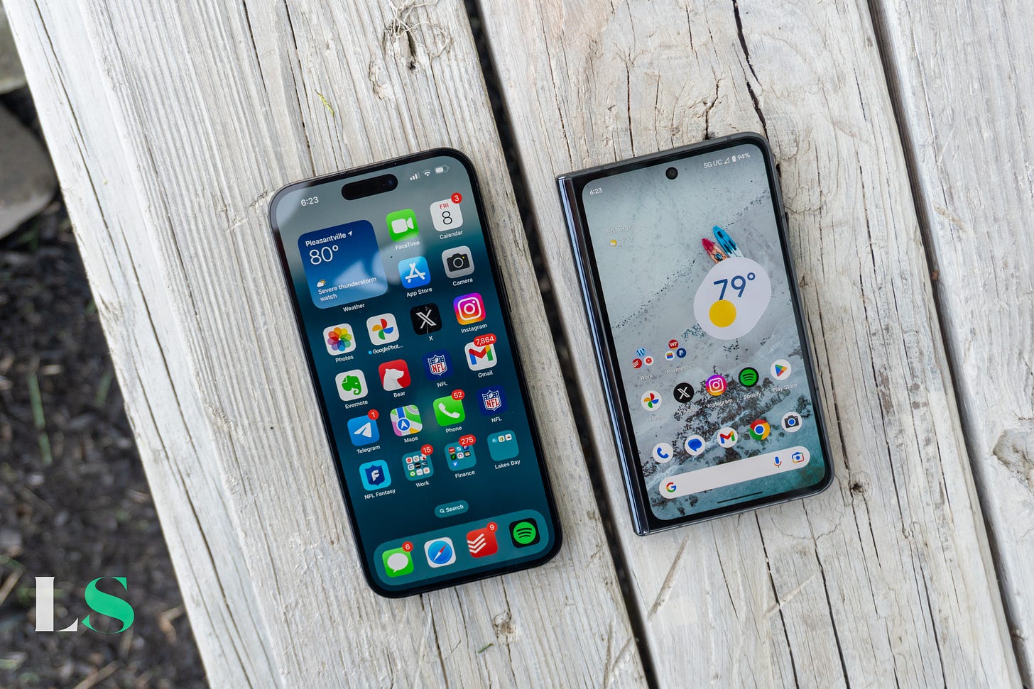 Apple iPhone 14 Pro Max next to the Google Pixel Fold on a wooden bench. Apple iPhone 14 Pro Max next to the Google Pixel Fold on a wooden bench.