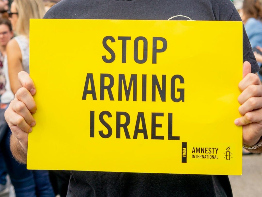 Man holds yellow sign saying stop arming israel