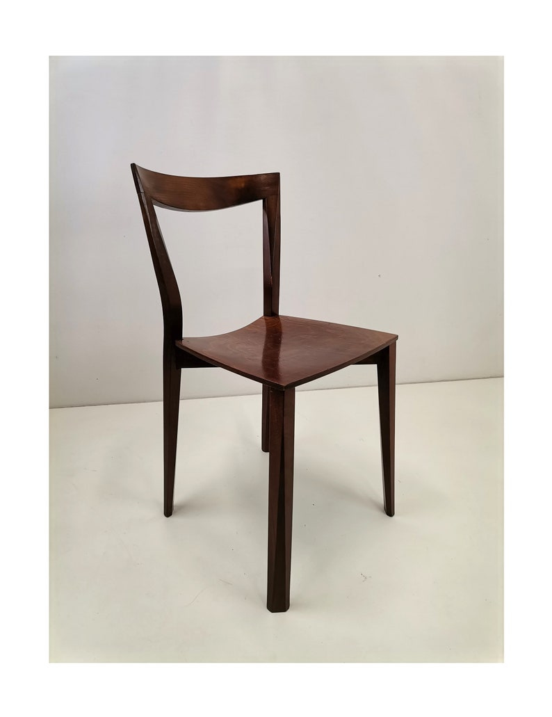 May include: A dark brown wooden chair with a curved back and four legs. The chair is on a white background.