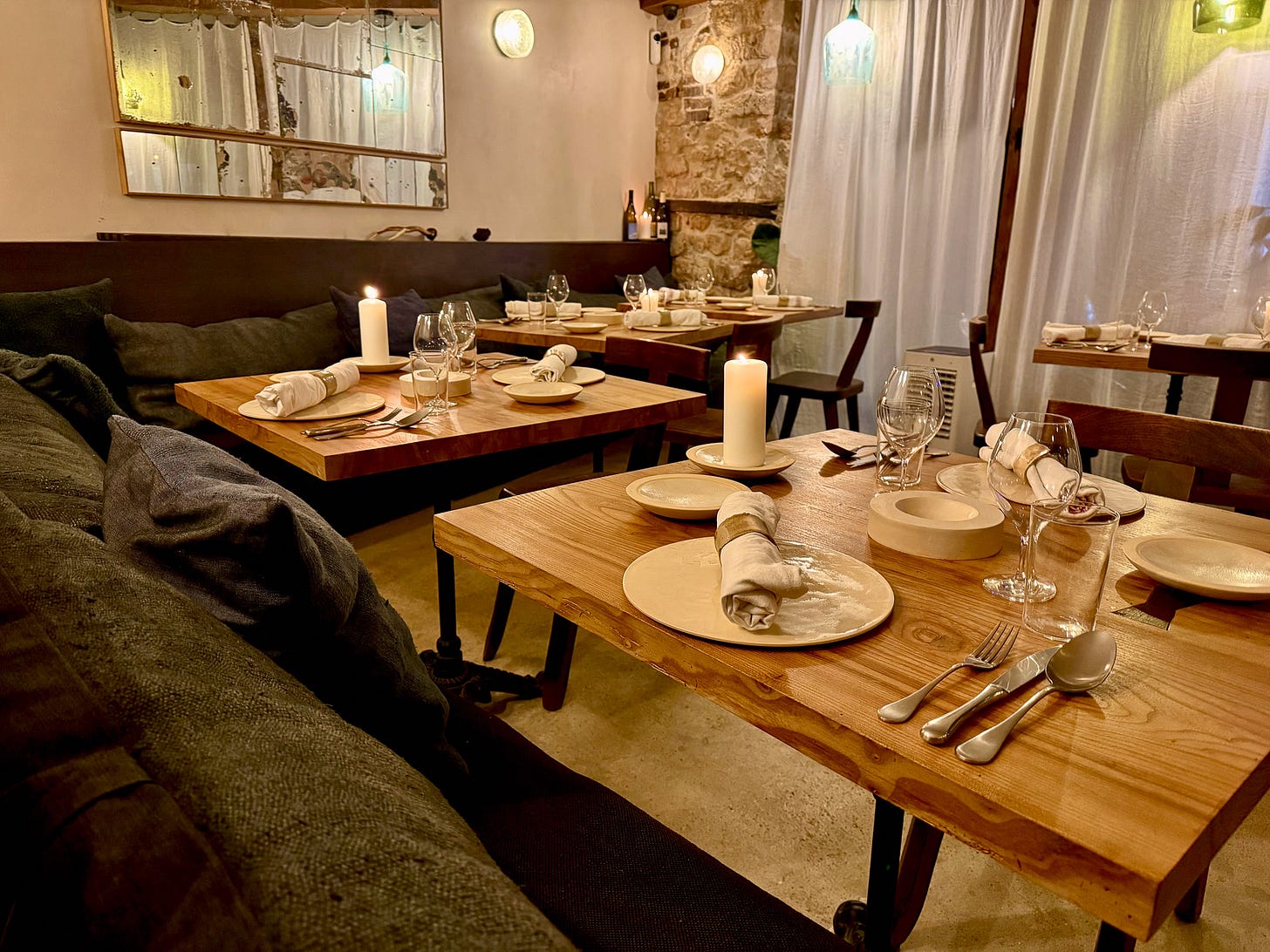 Candlelit dining room with deep banquettes and wood tables at Masaikuta, Paris 11th