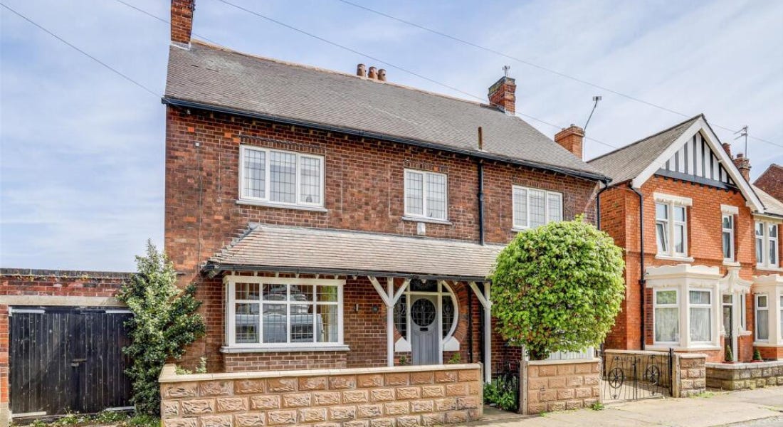 A house with brown bricks, white windows, and a grey door, with a blue sky above it A house with brown bricks, white windows, and a grey door, with a blue sky above it