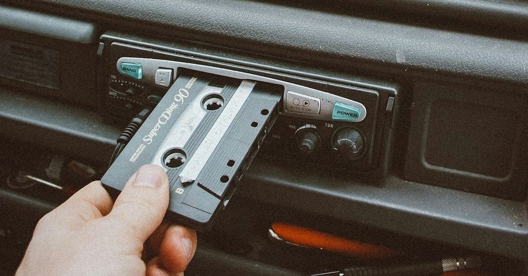 person inserting cassette tape on cassette player person inserting cassette tape on cassette player